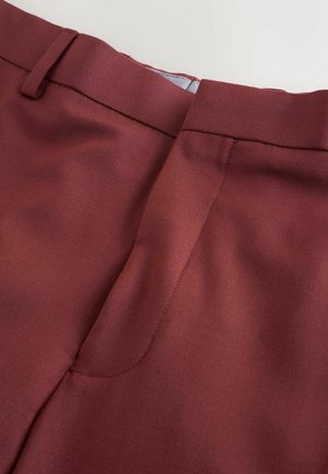 Bordó, szabott nadrág sima textúrával, lapos elülső derékrésszel és letisztult varrási részletekkel. Hivatalos öltözködéshez alkalmas.