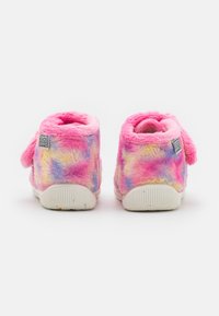 Pari värikkäitä pörrösandaaleja, joissa on vaaleanpunaisia, keltaisia ja sinisiä sävyjä, valkoiset pohjat ja "Gioseppo"-bränditagit takana.