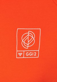 Una tela de color naranja brillante con una textura acanalada presenta un gráfico blanco que muestra un diseño entrelazado y el texto "GGI2" con un ícono de abeja.