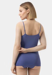 Blue fitted tank top with thin straps, smooth texture, and a mid-length design, featuring a seamless back and a subtle lower hemline.