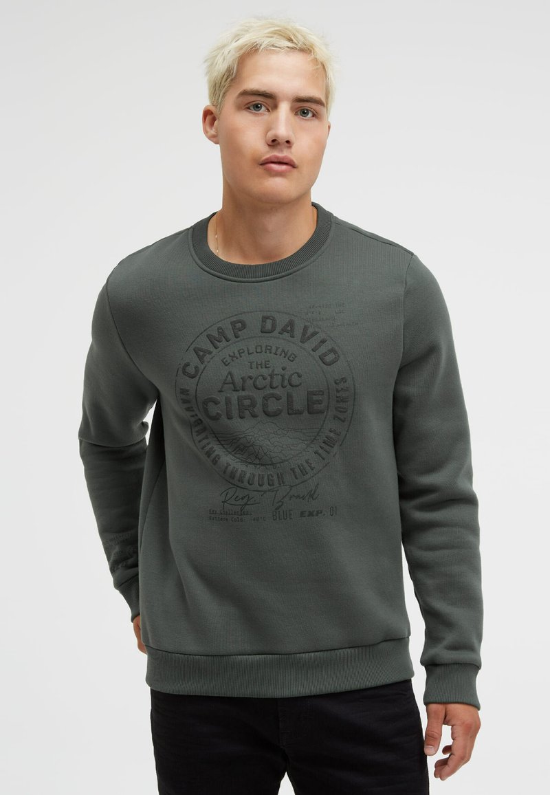Dark green sweatshirt with a round neck, ribbed cuffs, and a front graphic featuring "Camp David" and "Arctic Circle" in black print.
