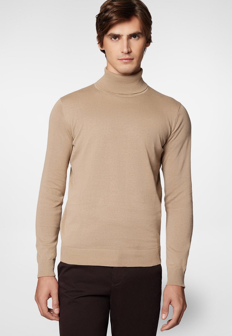 Beżowy sweter z golfem wykonany z miękkiej, prążkowanej dzianiny. Posiada długie rękawy i dopasowany krój, z ściągaczem u dołu i przy mankietach.