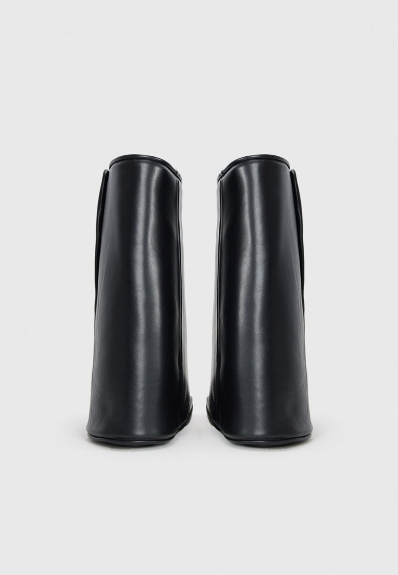 Bottines en cuir noir avec un design épuré, des têtes arrondies et une texture lisse, présentant des coutures minimales et sans matériel visible.