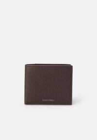Hnedá textúrovaná kožená peňaženka s kompaktným dizajnom, na prednej strane so subtilným strieborným logom Calvin Klein. Zaoblené okraje.