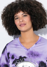 Fialové tričko s tie-dye vzorem a V-výstřihem, se stříbrným potiskem "POZITIVNÍ VĚCI." Měkká textura a ležérní design.