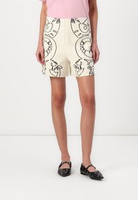 Shorts blancs avec des motifs abstraits noirs, dotés d'une taille ajustée et de poches latérales. Assortis à des ballerines noires avec des accents circulaires.
