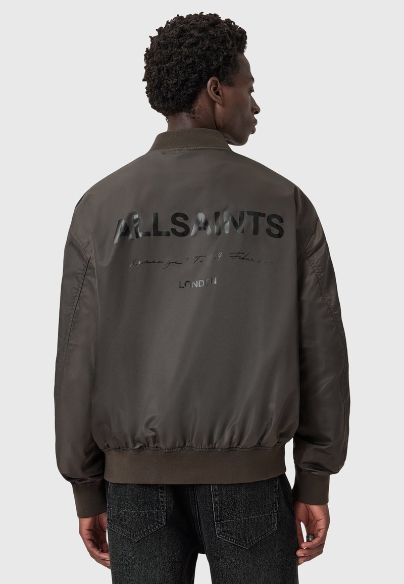 Giacca bomber marrone con un logo "ALLSAINTS" nero lucido sulla schiena, dotata di colletto a coste e orlo ed elastici ai polsini.