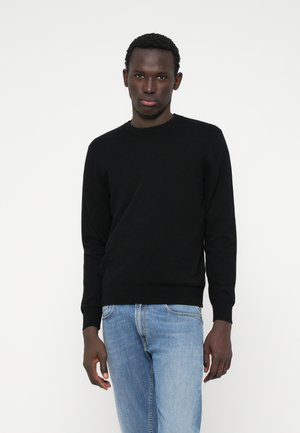 Sort crew-neck sweater med lange ærmer, lavet af et glat strikmateriale. Sammen med lyseblå denimjeans. Minimalistisk design, ingen synlige mønstre.