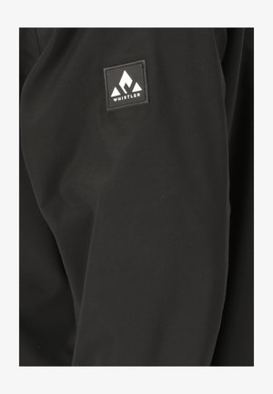 Sort jakke lavet af glat stof, med et firkantet logo-patch med hvide bjerggrafikker og teksten "WHISTLER."