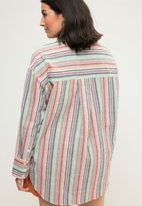 Gestreept shirt in meerdere kleuren: roze, groen, grijs en wit. Met knoopmanchetten, relaxte fit en een gebogen onderzoom. Lichtgewicht stof.