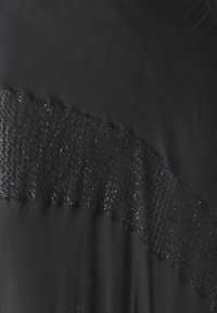 Doudoune noire avec un accent en volants texturé noir. Fini brillant avec une surface lisse. Présente un design épuré et une silhouette moderne.