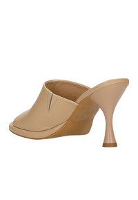 Mule beige in pelle con punta aperta, tacco curvato e cuciture dettagliate sulla tomaia. Design minimalista con una texture liscia.