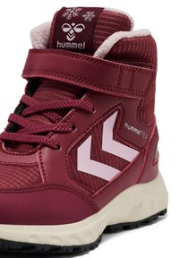 Burgundowe buty sportowe typu high-top z białą podeszwą, teksturowanym materiałem, sznurowadłami, paskiem na rzep oraz logo w kształcie chevronu z boku.