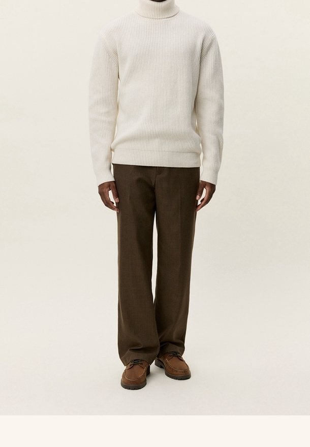 Pull à col roulé côtelé crème, pantalon large à carreaux marron, et chaussures marron à lacets. Coupe structurée, texture douce, et design confortable.