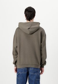 Hooded pullover in olive green, featuring a relaxed fit, ribbed cuffs, and a textured fabric. The back shows a smooth, simple design.