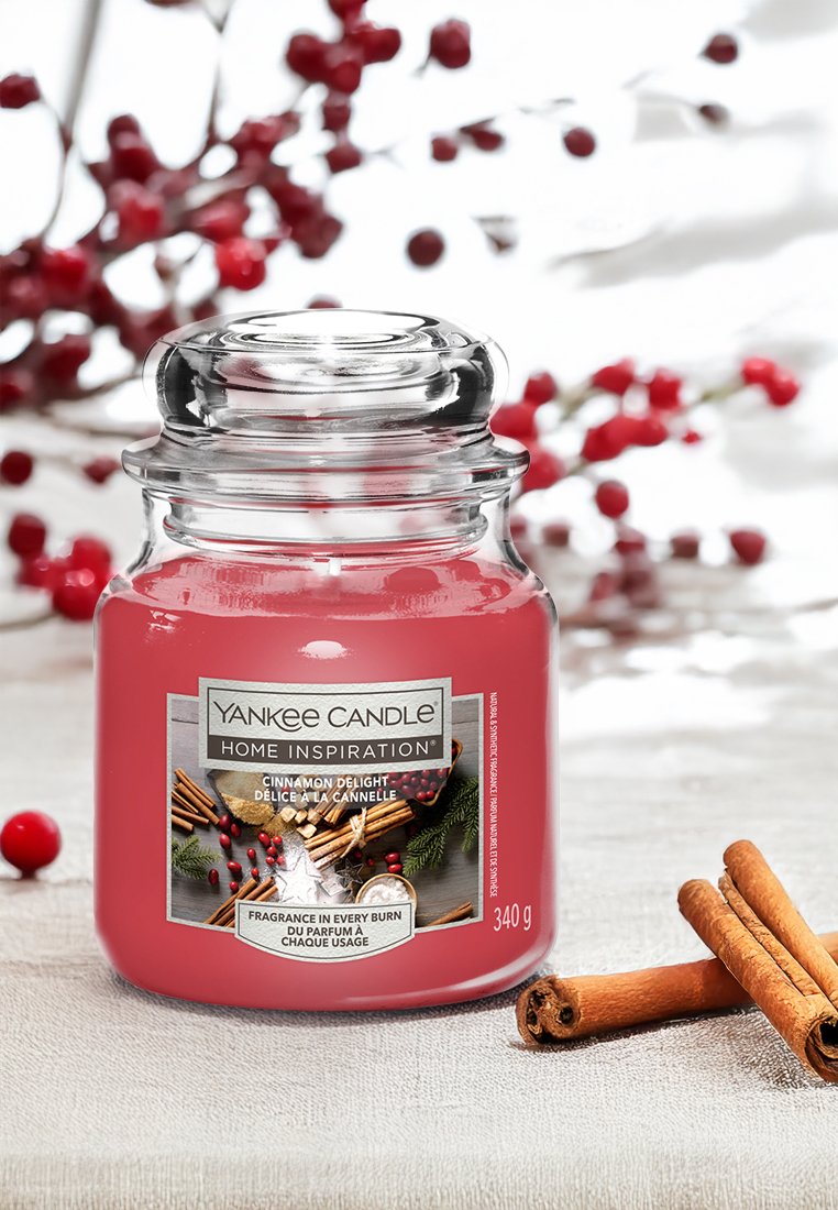 Yankee Candle in einem klaren Glasbehälter mit einem rosa Wachsinneren. Das Etikett lautet "Zimtgenuss." Enthält Zimtstangen und rote Akzente. 340 g.