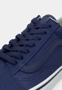 Tamno plavi suede tenesi s kontrastnim vezicama, gumeni potplat i strukturirani detalji duž bočne strane. Ima glatku površinu i šivane akcentne detalje.