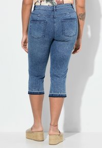 Blegede denim capri-bukser med mellemhøj talje, forkortet længde og frynset kantdetalje. To baglommer placeret over hofterne.