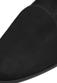 Svart mockaskor utan snörning med en slät yta, rundad framdel och platt sula. Minimalistiska accenter med en ren, strömlinjeformad design.