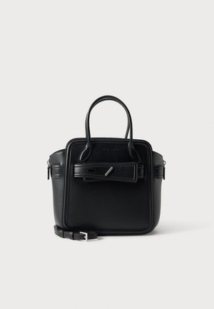 Sac à main en cuir noir avec deux poignées supérieures, détail de boucle à l'avant, et bandoulière réglable posé à côté sur un fond uni.