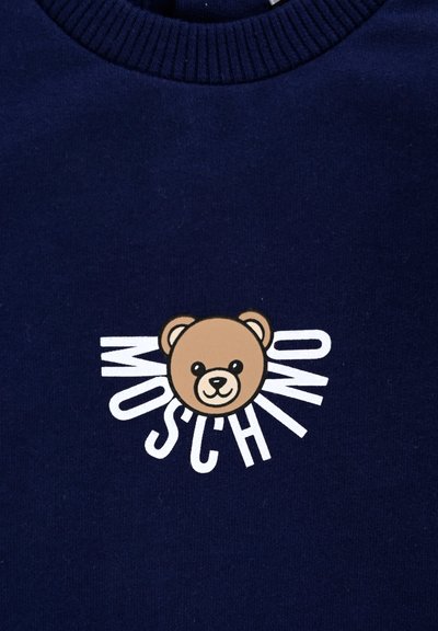 Granatowy sweatshirt z okrągłym dekoltem, na którym znajduje się logo w postaci kolorowego misia w odcieniach brązu i czerni, uzupełnione białym napisem "MOSCHINO."