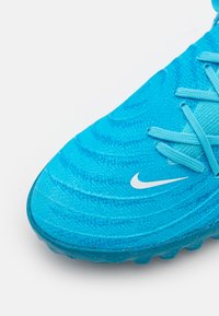 Modrá sportovní bota s texturovaným textilním svrškem, který má spirálové vzory, šňůrky v odpovídající barvě a bílé logo Nike na boku.