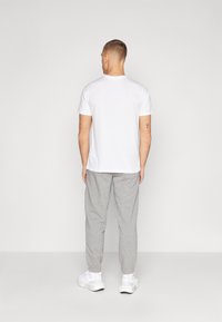 Witte T-shirt met korte mouwen, grijze joggingbroek en witte sneakers. Casual pasvorm met geribbelde halslijn, elastische tailleband en taps toelopende boorden.