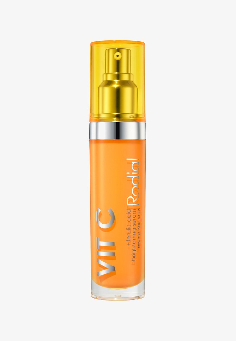 Heller orangefarbener Glasbehälter mit gelbem Pumpenkopf und silbernen Akzenten. Die Textetiketten tragen die Aufschriften "VIT C" und "Rodial". Glatte Oberfläche.