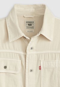 Kremowa koszula z denimu o klasycznym kołnierzyku, z dwiema przednimi kieszeniami, srebrnym wykończeniem i szczegółem w postaci czerwonej metki Levi's. Luźny krój.