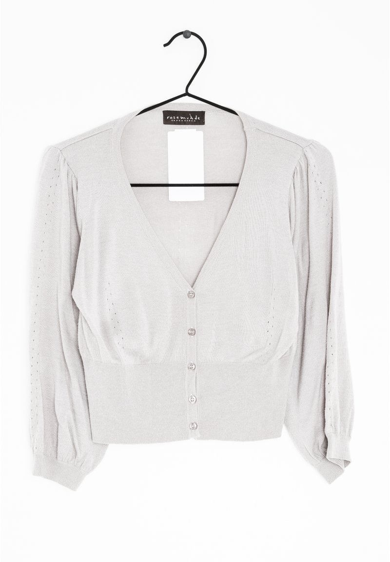 Ljusgrå kort cardigan i mjukt stickat material. V-ringning, puffärmar och fem knappstängningar framtill.