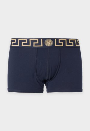 Boxer bleu marine avec ceinture à motif clé grec dorée et emblème central de tête de Méduse à l'avant.