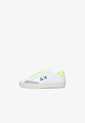 Sneaker bianca low-top con lacci e linguetta sul tallone giallo neon, dettaglio sulla punta in camoscio grigio e loghi geometrici neri sul lato.