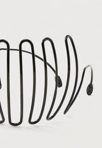 Black metal hair comb with curved, spaced prongs and two adjustable fasteners on a plain white background.