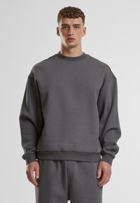 Felpa grigia con scollo rotondo, spalle dropped e polsini in costina. Realizzata in tessuto morbido, presenta una vestibilità comoda e un design minimal.
