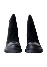 Stivaletti neri in suede con punta affusolata e tacco in pelle liscia nera. Suole spesse in gomma nera con battistrada sagomato.