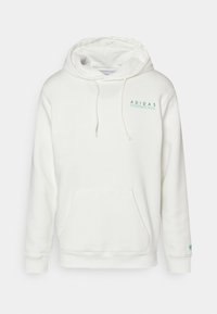 Vit hoodie i mjukt tyg. Har en kängorupocket, dragsko på huvan och texten "ADIDAS INTERNATIONAL" i grönt. Logotypdetalj på ärmen.