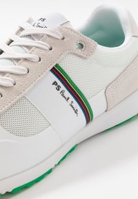 Weißer Sneaker aus Mesh und Wildleder mit einem morefarbigen Streifen und dem Logo "PS Paul Smith". Grüne Gummisohlen-Details sind sichtbar.