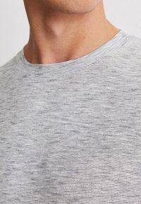 Grijs gestreept t-shirt close-up, met een zachte textuur en een ronde halslijn. Subtiele horizontale lijnen en minimale details.
