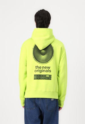 Neon green hoodie featuring a large speaker graphic and text "the new originals" on the back, with a smooth texture and ribbed hem.