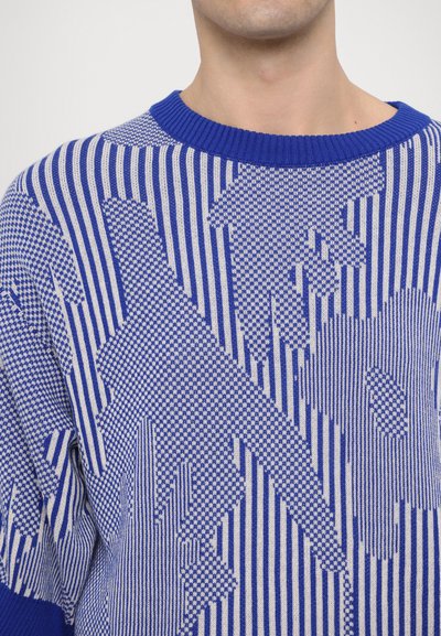 Strikket sweater med blåt og cremefarvet stribet mønster og abstrakte former, rund halsudskæring og ribbet tekstur.