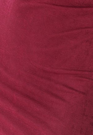 Karmesinroter, gerippter Stoff mit strukturierter Oberfläche, der feine vertikale Linien und subtile Farbintensitätsunterschiede zeigt.