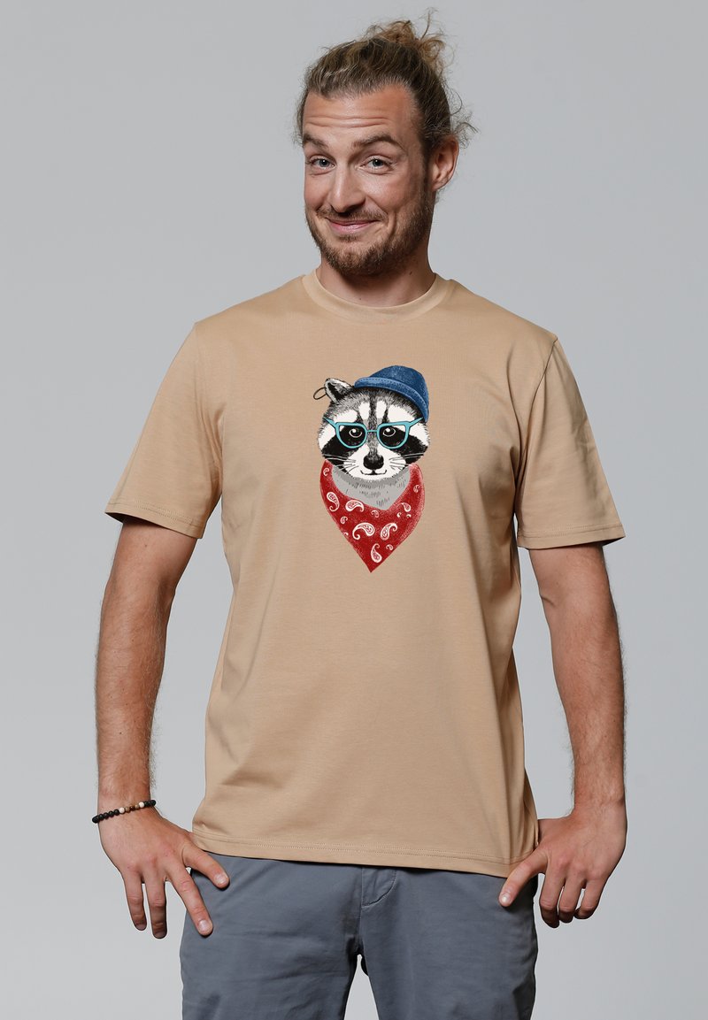 Beige Baumwoll-T-Shirt mit einer Illustration eines Waschbären, der einen blauen Hut und ein rotes Bandana mit weißem Paisleymuster trägt.