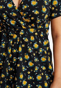 Black floral wrap dress featuring yellow roses and blue flowers, with short sleeves and a cinched waist detail. Soft fabric texture.