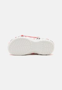 Semelle de chaussure en caoutchouc blanc avec un motif de bande de roulement texturé, ornée de personnages de dessin animé colorés en rouge, noir et gris.