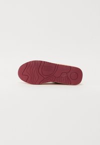 Red rubber shoe sole with textured grip patterns and engraved logo. Smooth beige upper visible at the edge. Size 37 mentioned.