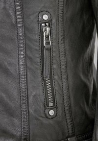 Schwarze Lederjacke mit einem Reißverschluss und metallischen Beschlägen, strukturierten Oberflächen und kontrastierenden Nähten.