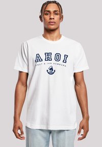 White cotton t-shirt featuring a navy graphic with "AHOI" text and an anchor design. Relaxed fit, short sleeves, crew neck style.