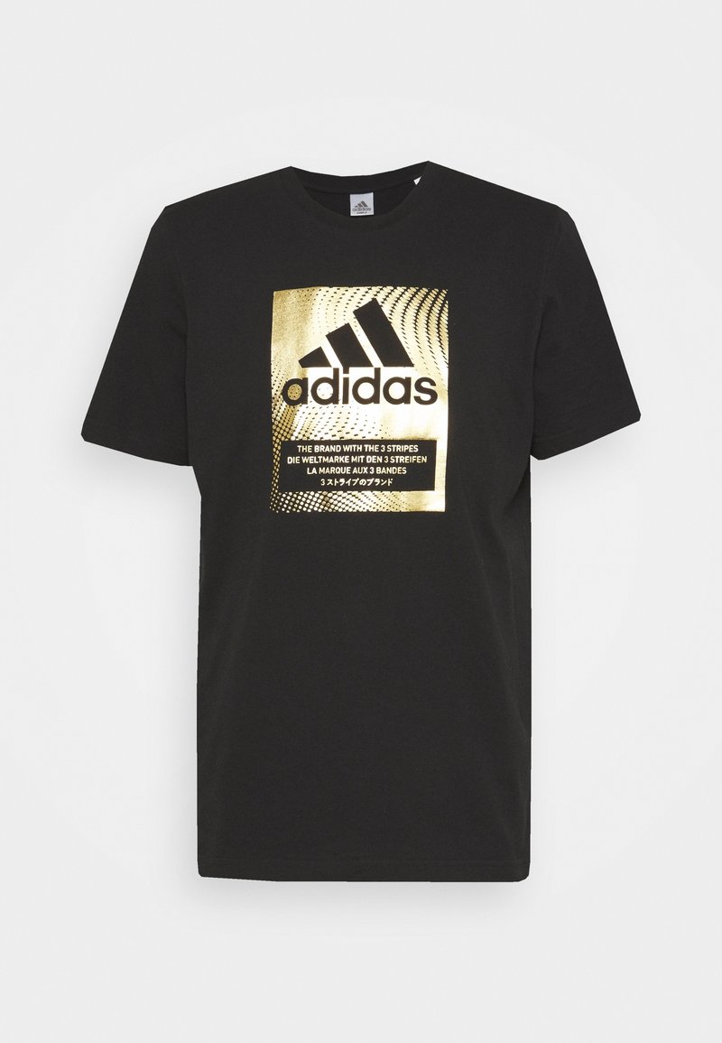 T-shirt noir Adidas avec un graphique rectangulaire doré présentant le logo Adidas et un texte multilingue sur les trois bandes de la marque.