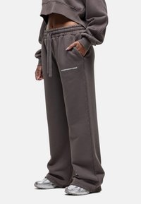 Grijze sweatpants met een ontspannen pasvorm, elastische tailleband, zijzakken en de tekst "GOODFORNOTHING" op de bovenbeen. Gepaard met zilveren sneakers.