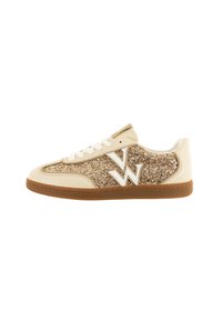 Zapatilla blanca y dorada con un panel lateral dorado brillante, acentos en beige, cordones blancos y una suela de goma marrón texturizada.